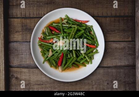 Top view Thai food stir fried morning glory on rustic wooden table Stock Photo