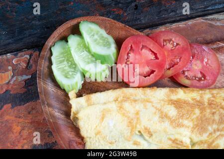 Plain egg omelette with tomato and cucumber isolated on rustic wooden background Stock Photo