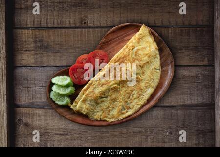 Top view of plain egg omelette with tomato and cucumber on rustic wooden background Stock Photo
