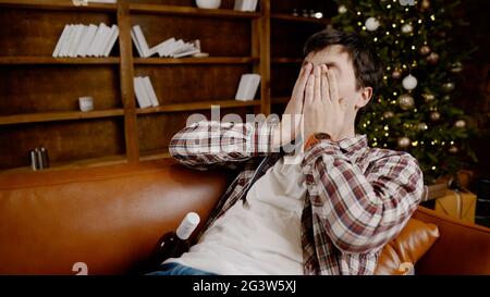 Young male alcoholic requires medical and psychological help. Man addicted alcohol and cannot stay on couch at home on Christmas Stock Photo