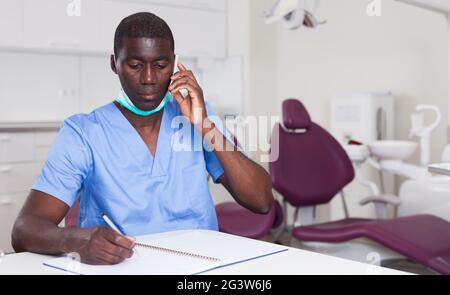 Dentist african american talking on mobile phone in office Stock Photo