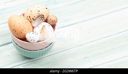 Chicken and quail eggs in bowl on wooden table. Easter eggs. With copy space Stock Photo