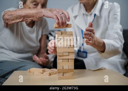 Mature doctor conducting session, therapy for senior patient in nursing home, training fine motor skills for dementia, alzheimer Stock Photo