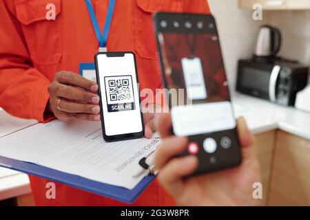 Close-up of unrecognizable client using smartphone camera while scanning QR code for payment of repair service Stock Photo