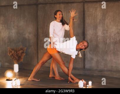 Woman with instructor practicing twisted yoga asana Stock Photo