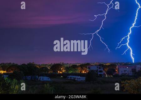 Two large and powerful lighting strikes crossing night blue sky Stock Photo