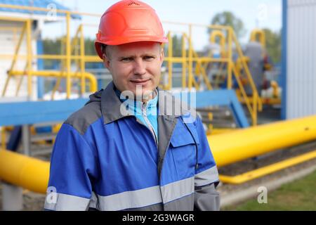 Engineer in hard hat and overalls at the production facility. a real portrait of a gas industry worker. Stock Photo