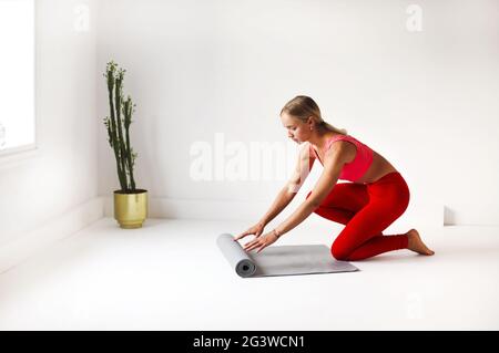Woman in sportswear preparing mat for yoga lesson Stock Photo