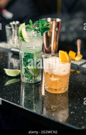 Several alcoholic cocktails at the bar in different glasses. Cocktail decoration: lime, mint, orange Stock Photo