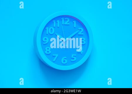 Cyan clock on pink painted wall. Minimal time concept. Chrismas eve or new year idea. Stylish analog clock hanging on wall, spac Stock Photo
