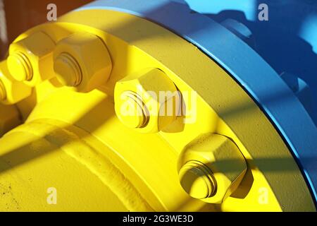 Two blue and yellow gas pipes are connected by large bolts and nuts. Background for suppliers of gas products and pipes. Stock Photo