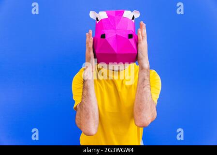 Cool man wearing 3d origami mask with stylish colored clothes - Creative concept for advertising, animal head mask doing funny things on colorful back Stock Photo