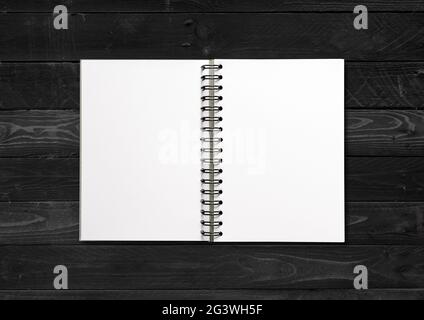 Blank open spiral notebook isolated on black wood background Stock Photo
