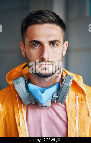 Close up portrait of handsome street artist staying on his graffiti painting background Stock Photo