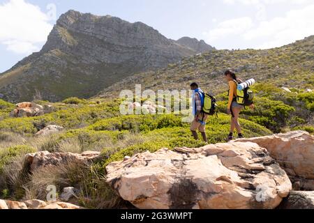 Fit afrcan american couple wearing backpacks hiking on the coast Stock Photo