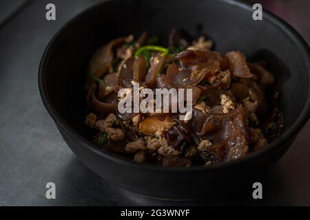 Stir-fried Wood ear and minced pork with scallion, garlic, and soy sauce. Homemade healthy Asian food. Food in a beautiful matt black bowl, close up t Stock Photo