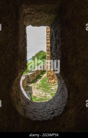 Symbolic image: View through a keyhole embrasure in the castle walls onto parts of the outer castle complex. Stock Photo