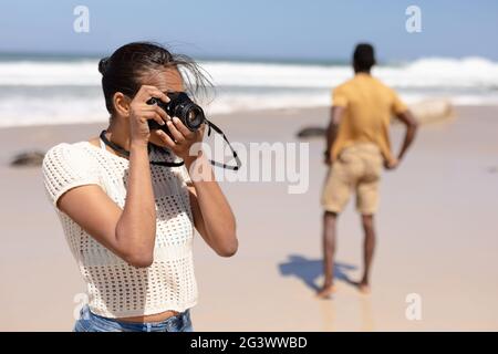 African american couple taking photos with camera on a beach by the sea Stock Photo