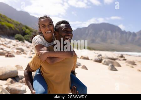 African american couple piggybacking on a beach by the sea Stock Photo