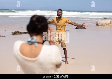 African american couple taking photos with camera on a beach by the sea Stock Photo