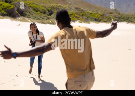 African american couple taking photos with camera on a beach by the sea Stock Photo