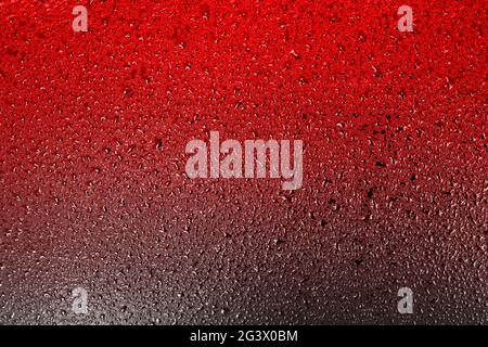 Red surface with drops of water or liquid with a gradient transition to a dark color. Stock Photo