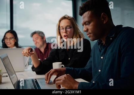 Diverse business colleagues using a laptop during a meeting at work in office Stock Photo