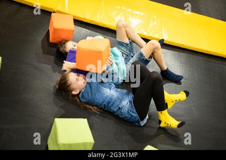Cute twin brother and sister jumping and bouncing on indoor trampoline together when spending time in children play center. Spor Stock Photo