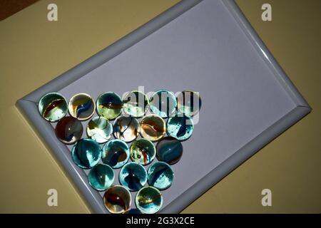 Yellow, green, blue and red glass marbles on a table. Stock Photo