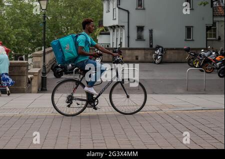 Deliveroo food courier cycling through Norwich city centre Stock Photo