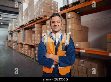 Cheerful man standing at manufacturing industry looking at camera with his arm crossed Stock Photo