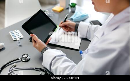 Unrecognizable female doctor using tablet while working Stock Photo