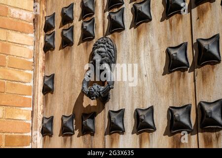 A massive wooden door with reinforced metal and old ornate lion door knocker Stock Photo