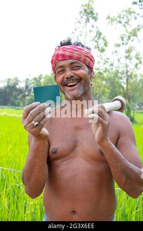 Rural Indian Farmer  Showing Business card  in agricultural field Stock Photo