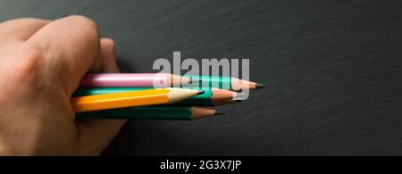 Several colored pencils in a man's fist, Close-up. Stock Photo
