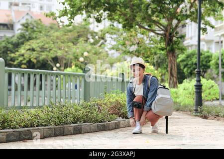 Attractive happy smile young adult asian woman traveller wear backpack. Using camera for photo journey Stock Photo
