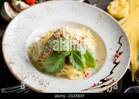 Italian pasta with parmesan cheese and creamy sauce and bacon. Spaghetti in a plate with herbs. Close-up. Concept - food, delica Stock Photo