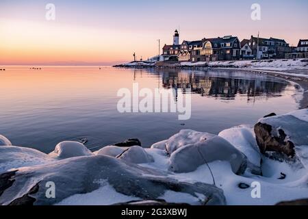 Winter in Urk with the dike and beach by the lighthouse of Urk snow covered during winter, sunset by the lighthouse of Urk Flevo