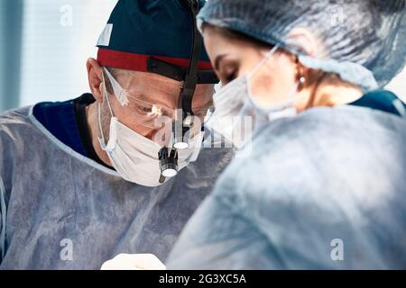 Surgeons men and women during an operation on the operating table, doctors in modern equipment perform operations on the heart Stock Photo