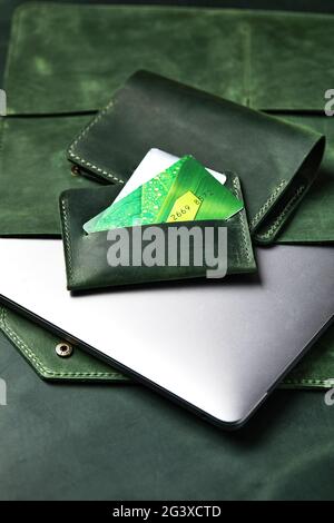 Leather case for a laptop, wallet, business card holder from green leather, handmade products on a wooden table, top view, close-up Stock Photo