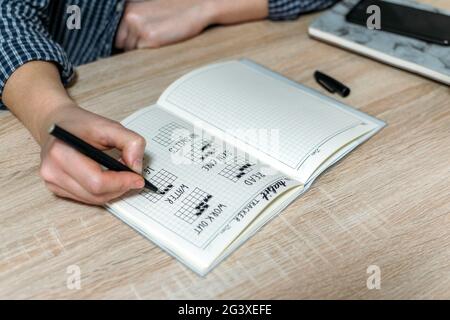 Bullet Journal, Habit Tracker. Female hand notes in habits tracker. Woman cross off day with routine in her Habit Tracker. Selective focus Stock Photo