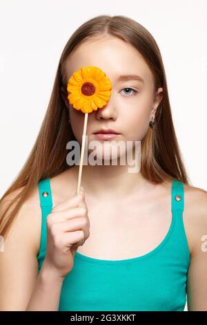 Teenager girl with with flower lollipop in hands closing eye. Stock Photo