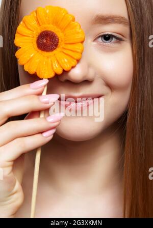 Teenager girl with  flower lollipop in hands closing eye. Stock Photo