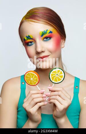 Teenager girl with unusual face art make-up and with lollipops in hands. Stock Photo