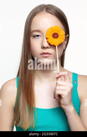 Teenager girl with with flower lollipop in hands closing eye. Stock Photo