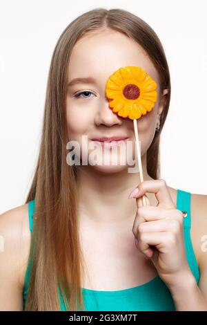 Teenager girl with flower lollipop in hands closing eye. Stock Photo