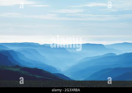 Aerial perspective in the mountains at sunrise. Thick blue fog in a mountain valley, plain in the early morning. Concept - trave Stock Photo