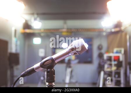 Microphone in recording studio, equipment and professional studio lighting in the blurry background Stock Photo