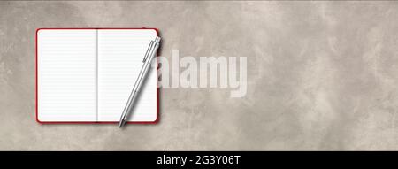 Red open lined notebook with a pen isolated on concrete background. Horizontal banner Stock Photo