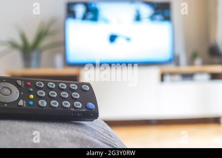 Remote control on the sofa, streaming on a smart TV. Stock Photo
